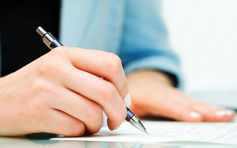 close up of a person's hands writing on a document