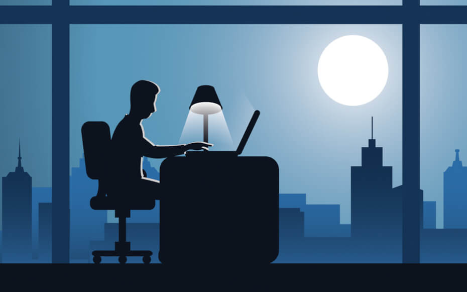 A silhouette of a man working at his office desk.
