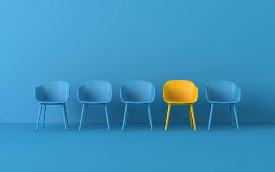 One yellow chair stands out among a group of blue chairs.