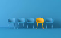 One yellow chair stands out among a group of blue chairs.