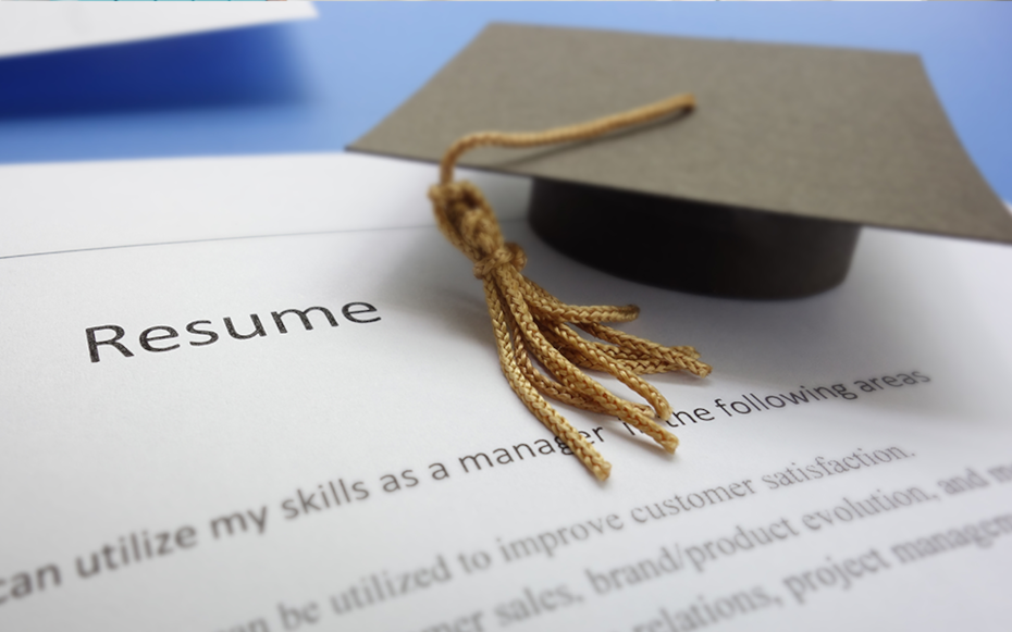 A graduation hat sits stop a resume.