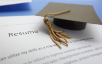 A graduation hat sits stop a resume.