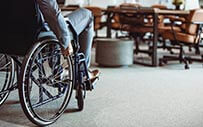 A person in a wheel chair enters a conference room.