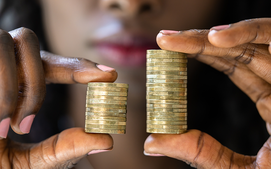 A woman examines an uneven stack of coins indicative of the widening gender pay gap.