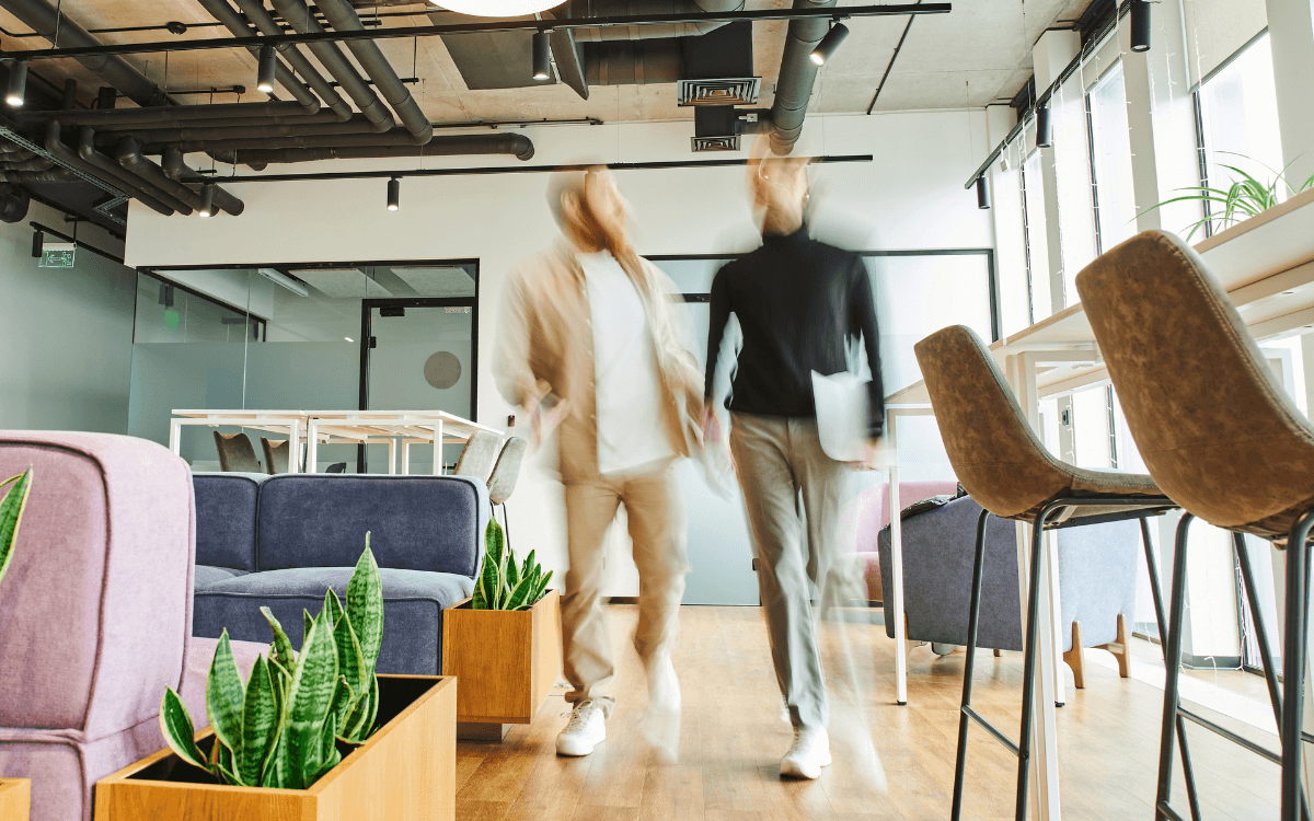 Two people walking and talking through an office.