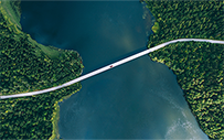 A car drives across a bridge that connects two forests.