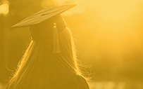 A college graduate looks off into the distance.