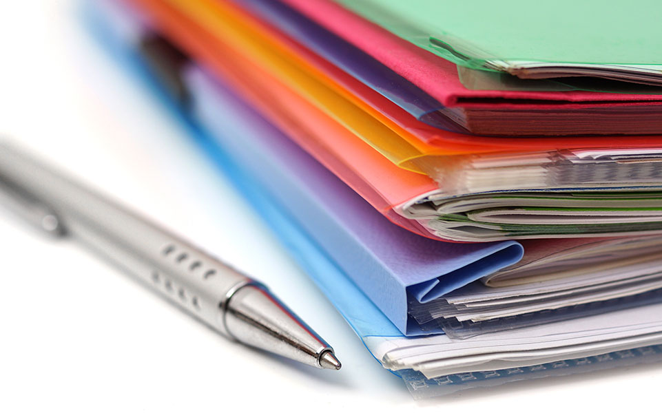 A stack of folders sits on a desk.