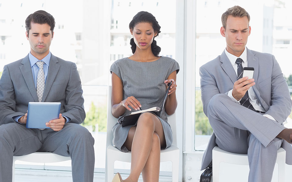 A woman sits between two men awaiting a job interview at an engineering firm.