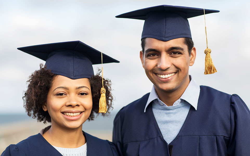 Two advanced degree college graduates smile on graduation day.