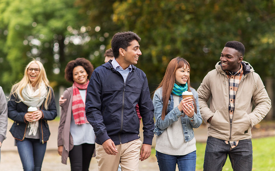 A group of international students walk on their college campus.