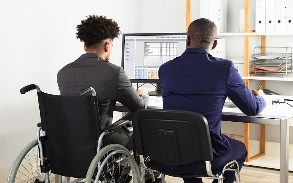 Two coworkers work together; one is in a wheelchair.