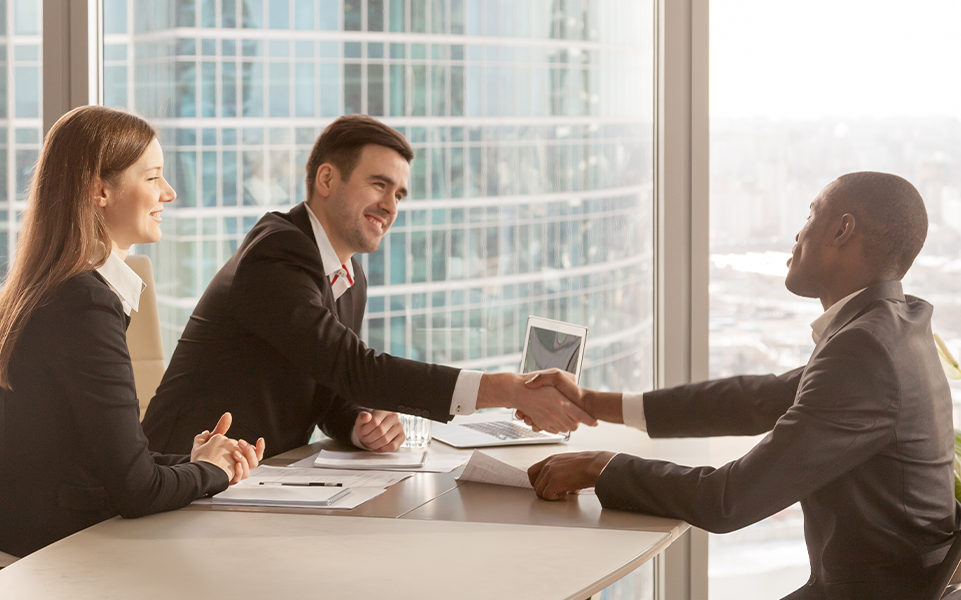 Recruiters shake the hand of a job candidate.
